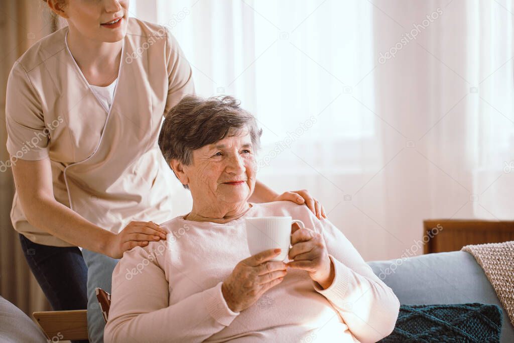 Older woman drinking tea in the living room in a nursing home