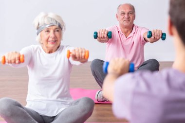 Genç eğitmenle spor salonundaki egzersizler sırasında birkaç aktif son sınıf öğrencisi.