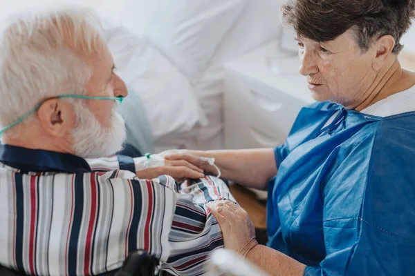 Besorgte Seniorin Spricht Mit Ihrem Kranken Mann Mit Sauerstoffmaske Stockbild