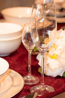 Şampanya bardakları ve bir buket suni çiçekle süslenmiş yemek masası.