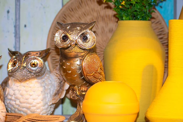 Dairenin dekoratif dekorasyonu, bronz baykuşlar ve çiçekli sarı vazo.