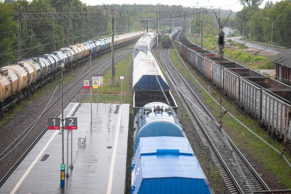 Duran yük vagonları ve tanklarıyla yağmurlu havada tren istasyonu.