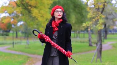 Şemsiyeile sonbahar parkında dans eden ve şarkı söyleyen kadın