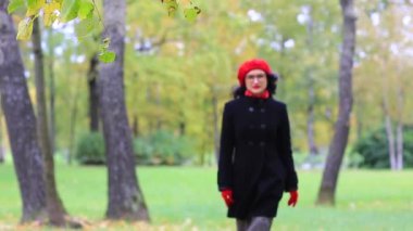 Güzel bir kadın yürür ve sonbahar Park yansıtır