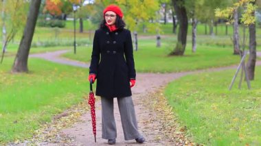 Sonbahar parkında kırmızı şemsiyeli kadın