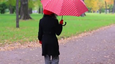 Sonbahar parkında kırmızı şemsiyeli kadın.