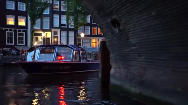 Večerní pohled na Amsterdam. Kanály, lodě procházející pod mostem vyzdobené osvětlením, architekturou a světly. — Stock video