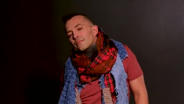 Medium close-up of man, isolated on a black background with scarf, looking at the camera and expressing emotions — Stock Video