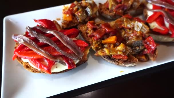Хрустящая брускетта с анчоусами, маринованный красный перец и тушеные баклажаны и помидоры — стоковое видео