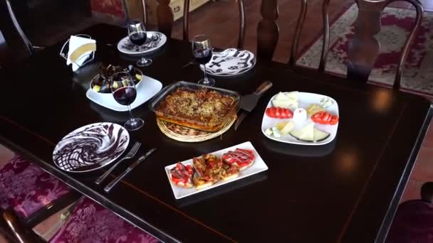 Table set for three persons. Vegetable casserole, cheese plate, anchovy bruschetta, lemon mussels and red wine. — Stock Video