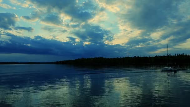 Речная лодка движется по вечернему озеру, создавая волны в лучах заката и отражениях в воде — стоковое видео
