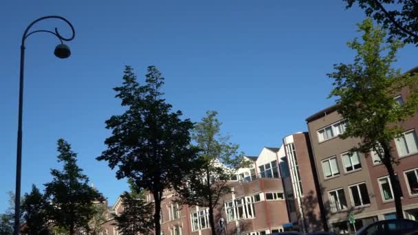 가로등의 실루엣, 푸른 하늘의 대각선, 암스테르담 중심가에 있는 오래 된 집들, 길을 걷고 있는 사람들의 실루엣. 제목을 위한 빈 칸. — 비디오