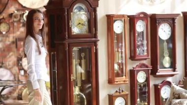 Kız saat dükkanından büyük duvar saatini seçiyor.