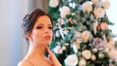 Gece elbisesi giymiş güzel bir kız Noel ağacıyla süslenmiş bir odada hayal kuruyor..