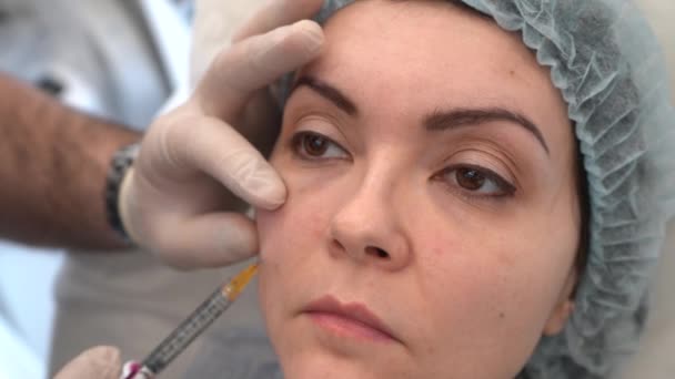 Лікар в білих рукавичках заповнює сльозогінну паз на обличчі жінки — стокове відео