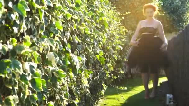 Una hermosa chica con piel blanca y pelo rojo en el jardín en un día soleado — Vídeos de Stock