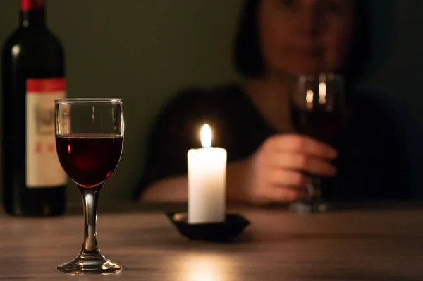 a glass of red wine on the background of a candlestick and a girl