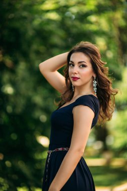 Mavi elbiseli güzel bir kız parkta yürüyor. Güneşli bir gün. Yaz