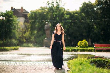 Bir kız büyük bir çeşme yakınındaki şehir etrafında yürüyor. Güneşli bir gün. Yaz