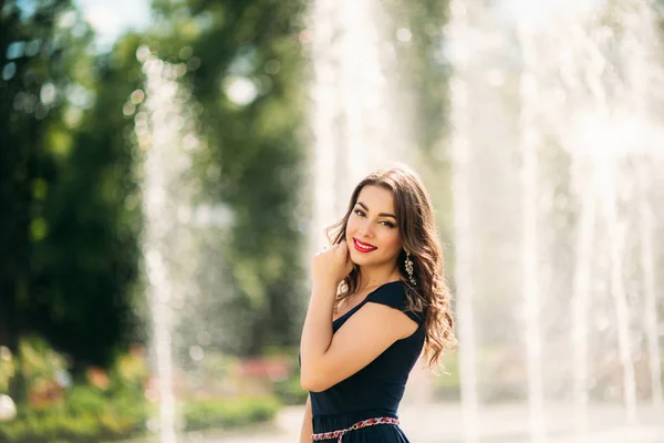 Una chica está caminando por la ciudad, cerca de una gran fuente. Día soleado. Verano — Foto de Stock