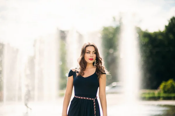 Una chica está caminando por la ciudad, cerca de una gran fuente. Día soleado. Verano — Foto de Stock