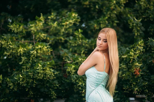 Блондинка в бірюзовій кольоровій сукні позує фотографу — стокове фото