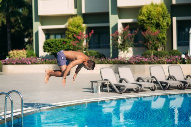 Genç adam Resort'ta yüzme havuzunda atlama