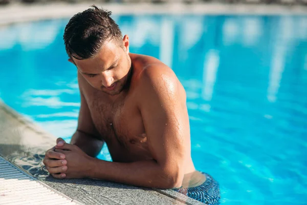 Primer plano retrato de un joven atractivo descansando en el borde de la piscina — Foto de Stock