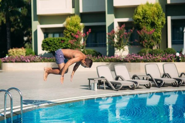 Νεαρός άνδρας άλματα στην πισίνα στο resort — Φωτογραφία Αρχείου