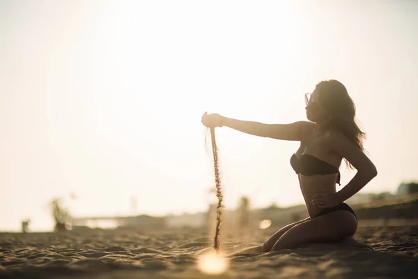 Sexy meisje zonnebaden op een strand en speelt met zand — Stockfoto