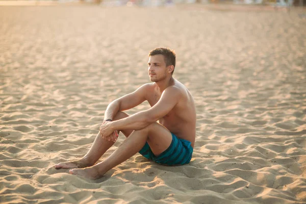 El hombre se sienta en la playa de arena — Foto de Stock