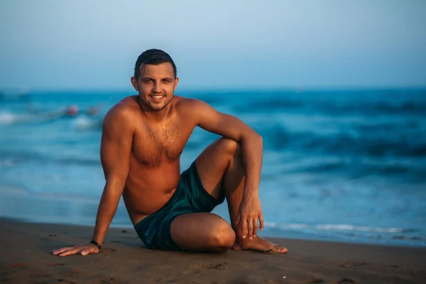 Jóképű férfi, homokos strandon helyezkedik el, a tengerparton — Stock Fotó