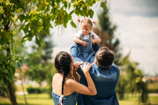 Fericit fericit tânăr tată de familie, mamă și fiică mică se distrează în aer liber, jucându-se împreună în parc de vară, în mediul rural. Mamă, tată și copil râzând și îmbrățișându-se, bucurându-se de natură afară — Fotografie, imagine de stoc