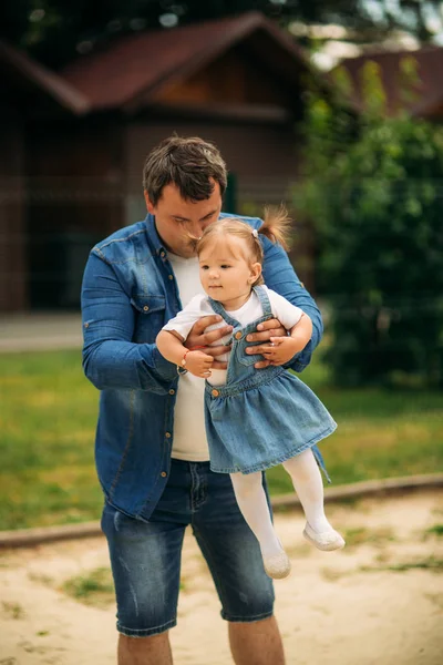 Vader en dochter gekleed in jeans, wandelen in de pakr en veel plezier — Stockfoto