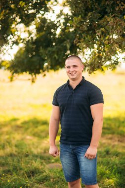 Büyük bir yeşil ağaç yakınındaki çekici adam stand. Aşk hikayesi