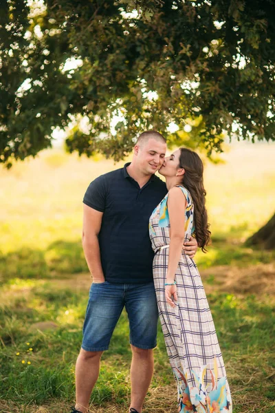 Un bel ragazzo e una bella ragazza si abbracciano vicino a un grande albero verde. Storia d'amore — Foto Stock