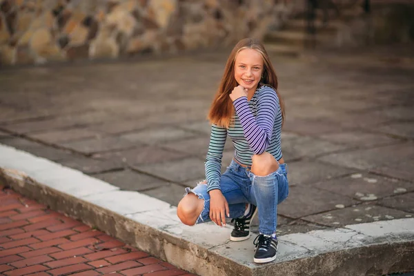 Jonge tiener houdingen voor foto. blond meisje in spijkerbroek en blouse — Stockfoto