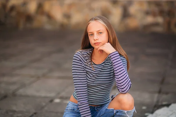 Jonge tiener houdingen voor foto. blond meisje in spijkerbroek en blouse — Stockfoto