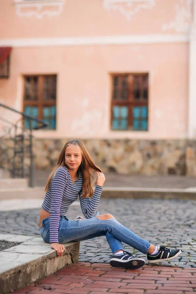 Joven adolescente posa para la foto. chica rubia en jeans y blusa. jugar con el pelo —  Fotos de Stock