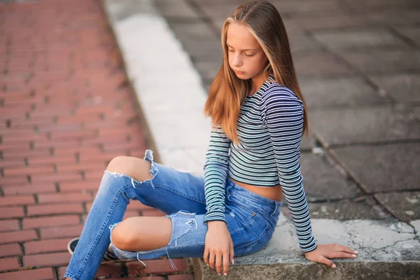 Jonge tiener houdingen voor foto. blond meisje in spijkerbroek en blouse — Stockfoto