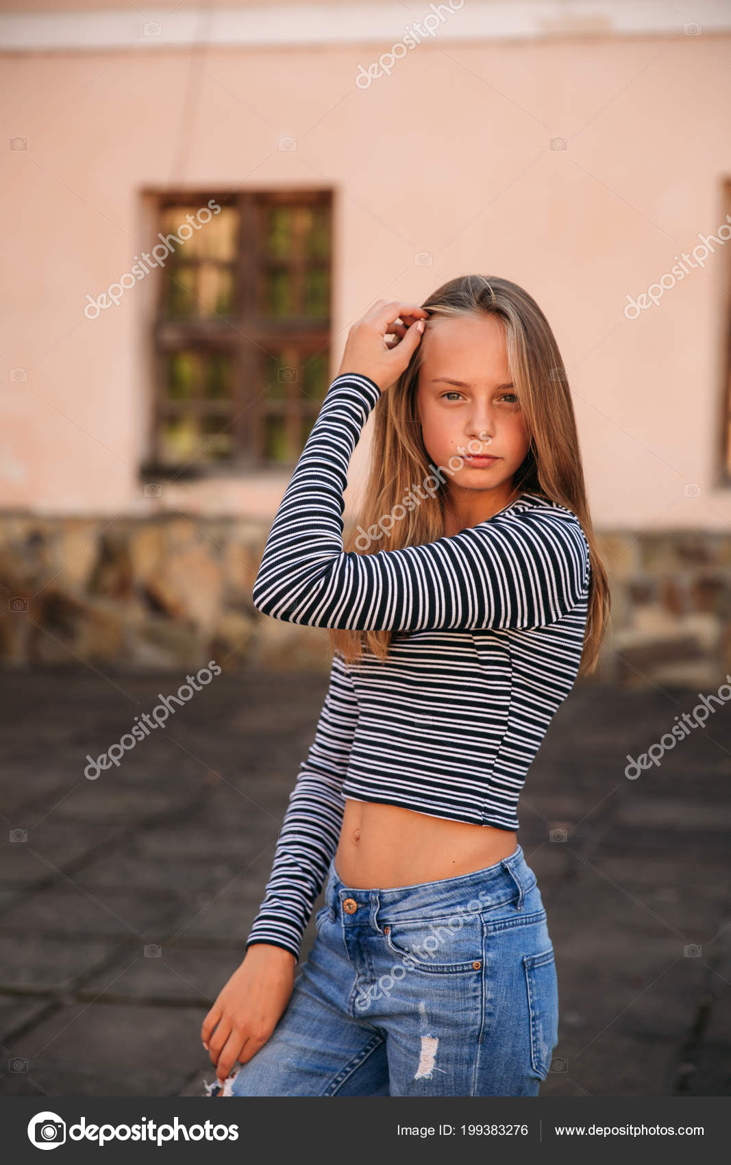 Young teenage poses to photographer. blonde girl in jeans and