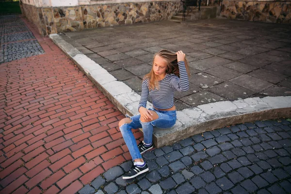 Jonge tiener poses aan fotograaf. blond meisje in spijkerbroek en blouse — Stockfoto