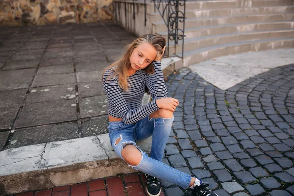Young teenage poses to photographer. blonde girl in jeans and blouse — Stock Photo, Image