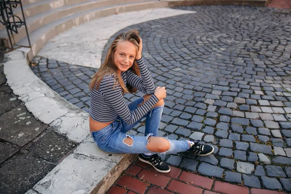 Joven adolescente plantea a fotógrafo. chica rubia en jeans y blusa —  Fotos de Stock