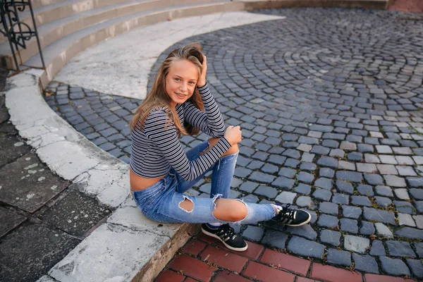 Jonge tiener poses aan fotograaf. blond meisje in spijkerbroek en blouse — Stockfoto