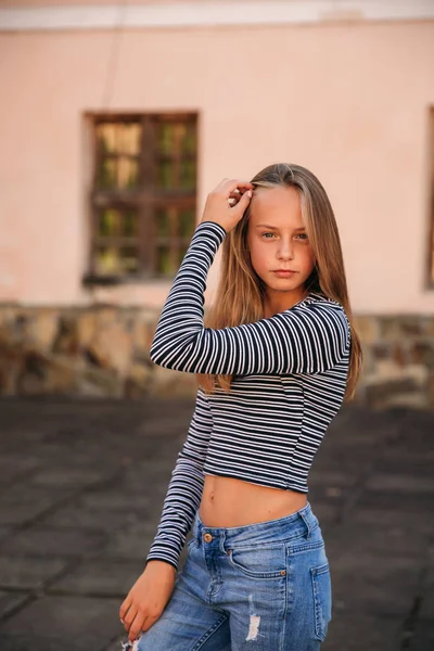 Jonge tiener poses aan fotograaf. blond meisje in spijkerbroek en blouse — Stockfoto