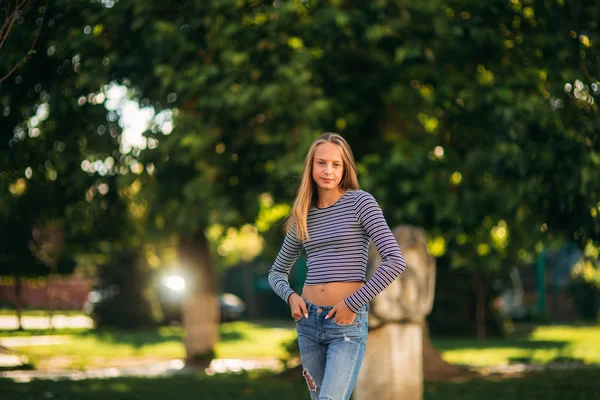 Ξανθιά εφηβικό κορίτσι σε Ριγέ μπλούζα για το backgrountd του πράσινου δέντρου — Φωτογραφία Αρχείου