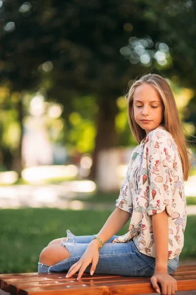 Молодая девушка-подросток сидит на скамейке — стоковое фото
