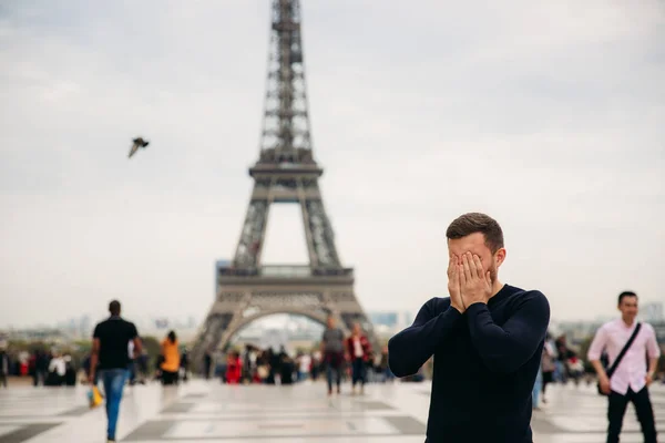 Vidám ember a sötét kék pulóver áll a háttérben az Eiffel-torony — Stock Fotó