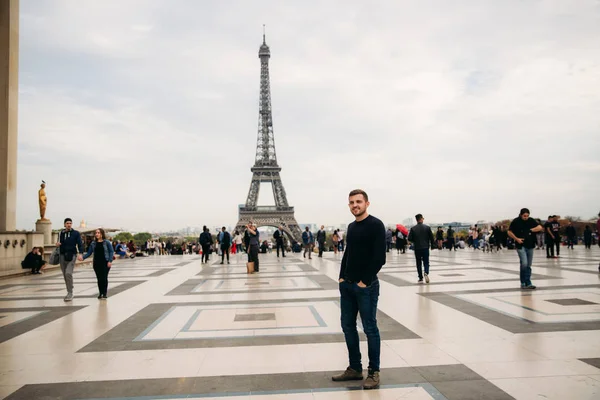 Hombre guapo con un jersey azul oscuro está de pie en el fondo de la Torre Eiffel — Foto de Stock